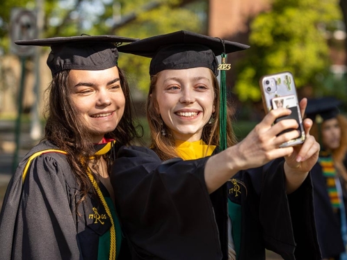 Two graduates taking a selfie.