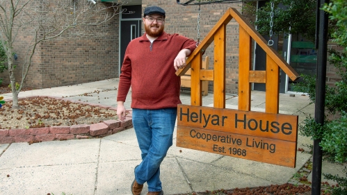 A student standing next to the Helyar House sign.