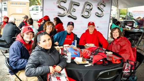 Six alumni sitting in front of balloons that spell out SEBS.