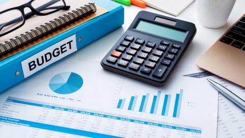 A calculator, reading glasses, and a budget spreadsheet.