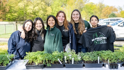 Six students standing behind a table of seedlings for sale.