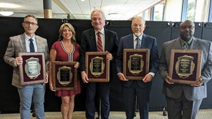 Five alumni holding awards.