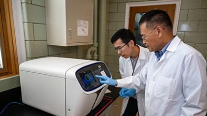 Two researchers operating a lab machine.