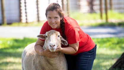 A person posing with a sheep.