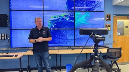 An oceanographer standing in front of a large monitor with a map on it.