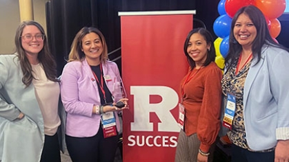 Four people standing around a banner that reads, 'R Success".