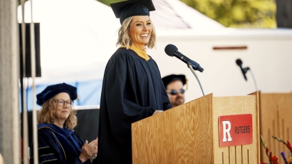 Dylan Dreyer standing at a podium in graduation regalia.