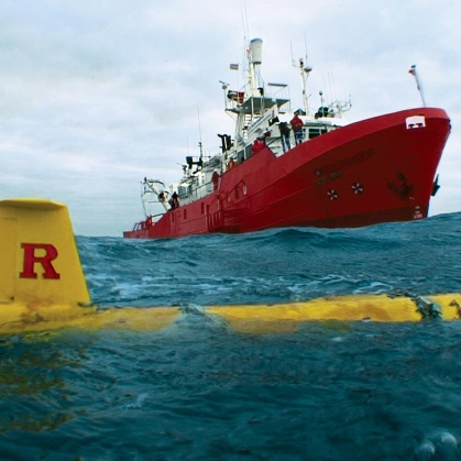An underwater glider With a Rutgers 'R' in it surfaced near a research ship.