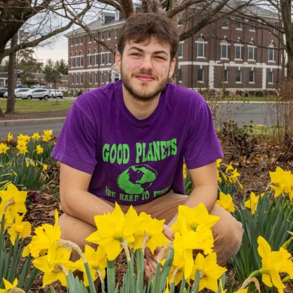 Josh Kover crouching in a bed of flowers.
