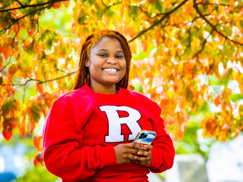 A smiling student holding a cellphone.