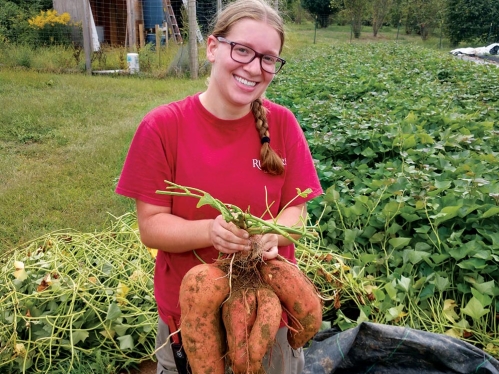 A student holding a bunch of root vegetables.