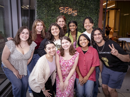 A group of students in front of a 'SEBS' sign.