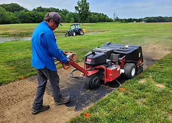 A researcher operating equipment on a turf plot.